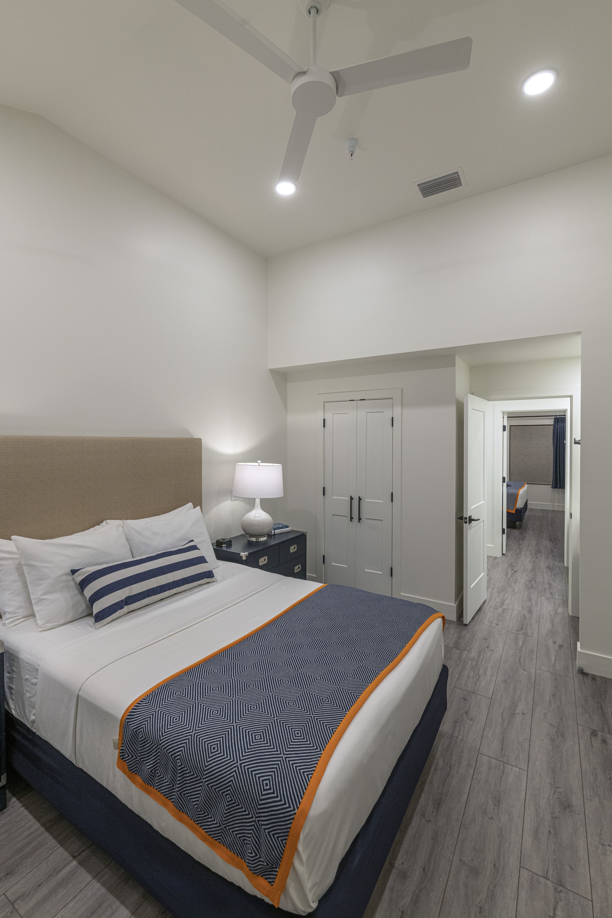 Een moderne hotelkamer met een groot bed, een plafondventilator en een inloopkast.