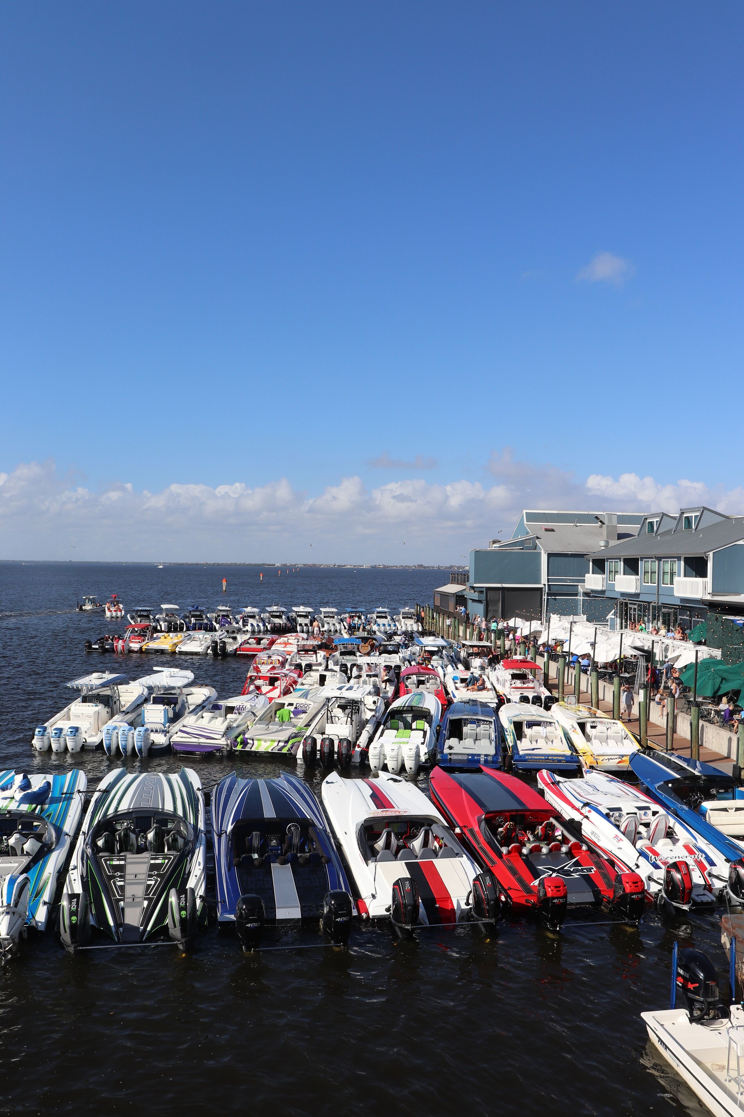 A marina with various boats docked, a pier, and a building in the background.