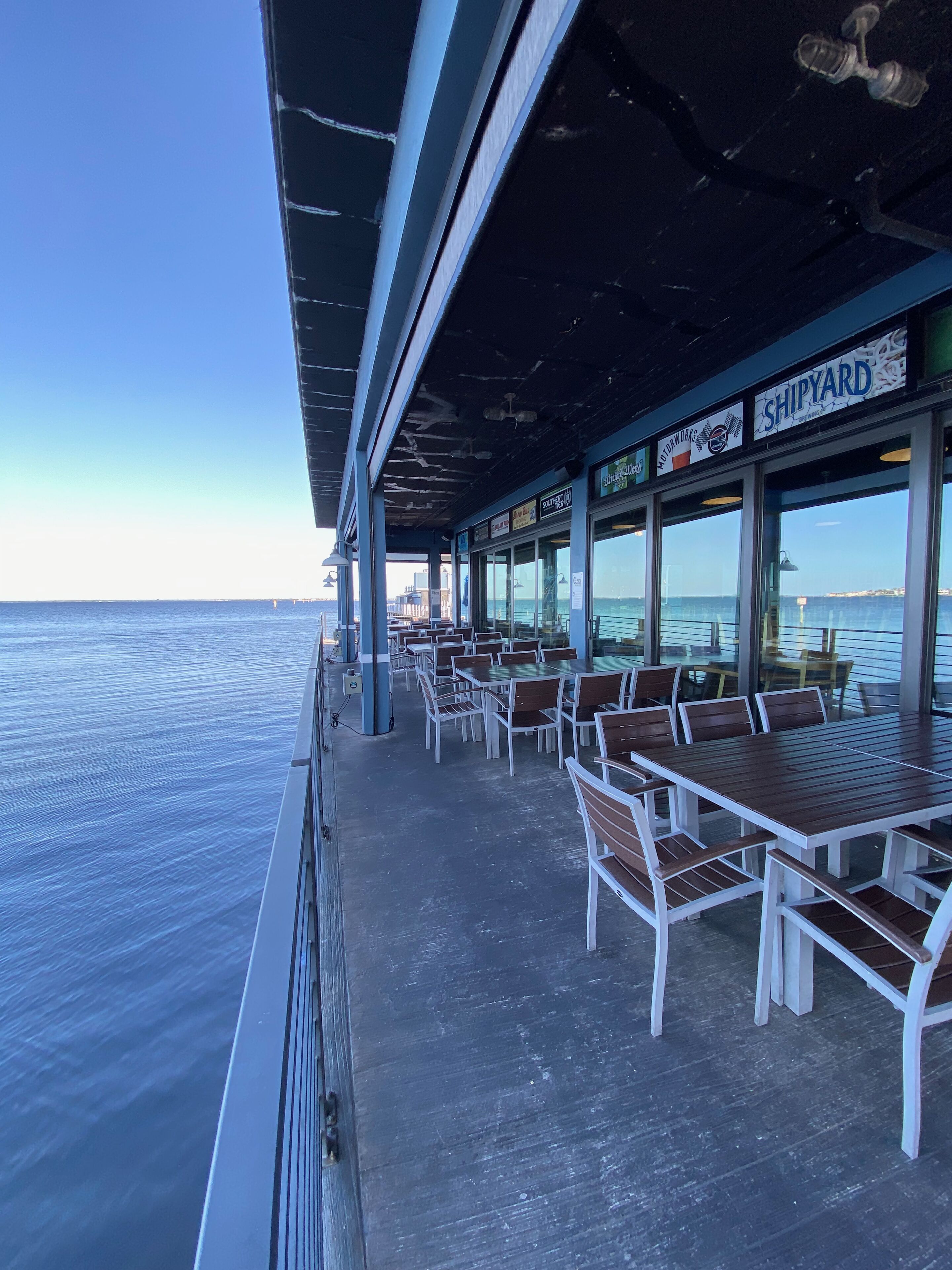 Un espace extérieur abrité, aménagé avec des tables et des chaises, et offrant une vue sur la mer.