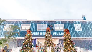A building with the sign "Hermes Village" and decorated Christmas trees in front.