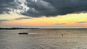 Água calma com um barco ao primeiro plano e uma linha de costa distante.