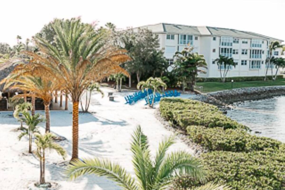 A hotel with a pool, palm trees, and a white building with multiple windows.