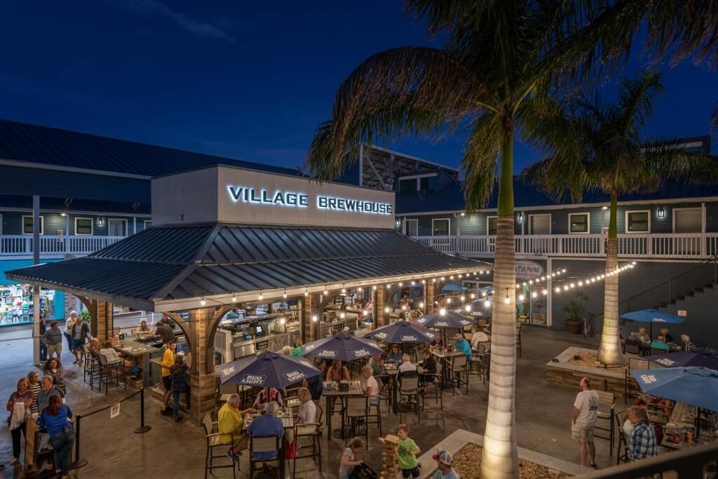 Une brasserie de village avec une terrasse et des palmiers.