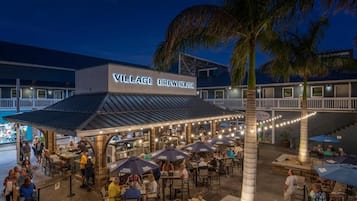 A Village Brewhouse with outdoor seating and palm trees.