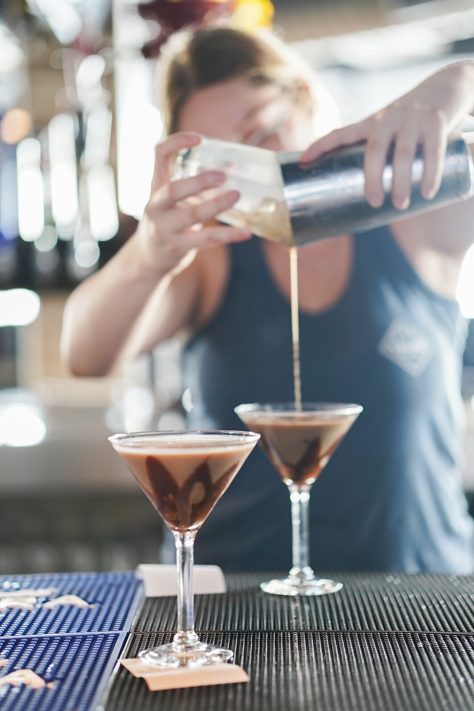 A bartender pouring a drink into a martini glass.