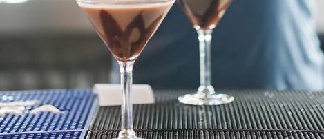 A bartender pouring a drink into a martini glass.
