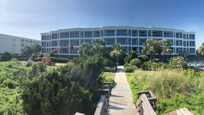 Un hotel moderno con un patio central, un paseo marítimo de madera y una zona de piscina.