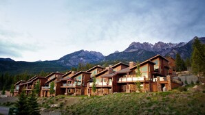 Una hilera de modernas cabañas de madera con amplias ventanas, frente a un paisaje montañoso.