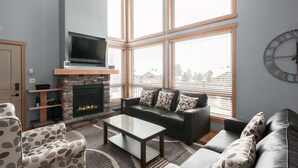 Una sala de estar moderna con chimenea, sofás de cuero y un televisor de pantalla plana.