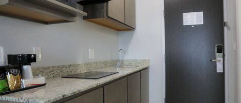 A kitchen with a granite countertop, a microwave, and a dark wooden door.