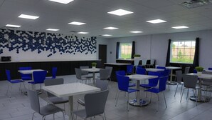 Un espace de restauration moderne avec des chaises bleues et grises, des tables blanches et un motif décoratif sur le mur.
