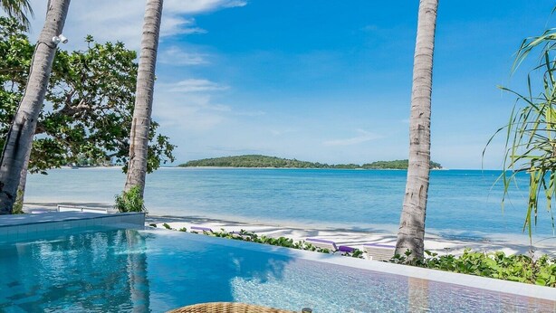 A poolside breakfast setup with a wicker tray, surrounded by palm trees and a clear view of the sea. - La Vida Samui (Koh Samui)