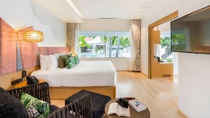 A hotel room with a bed, a TV, a desk with a chair, a window with a view of the outdoors, and a phone on the nightstand. - La Vida Samui (Koh Samui)