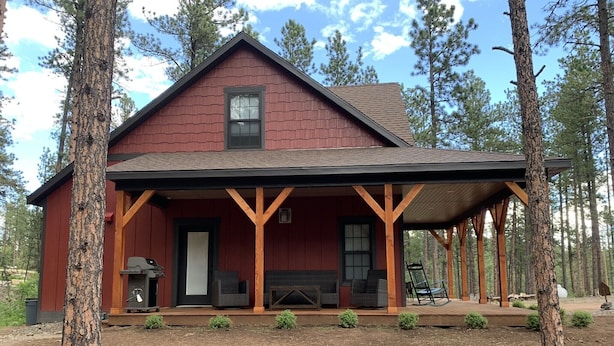 A rustic cabin with a covered porch, a fireplace, and outdoor seating.