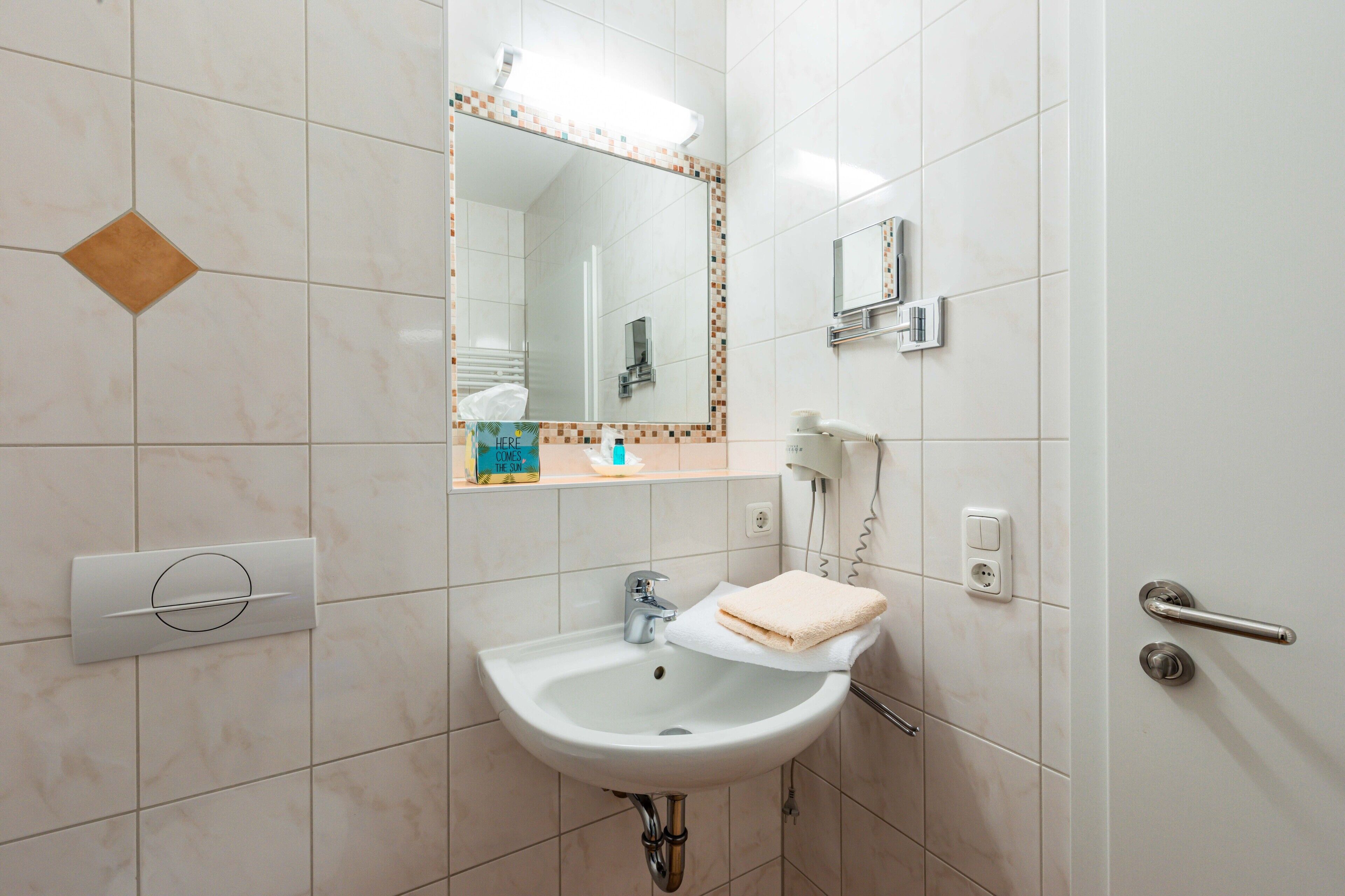 A bathroom with a sink, mirror, towel, and a door with a handle.