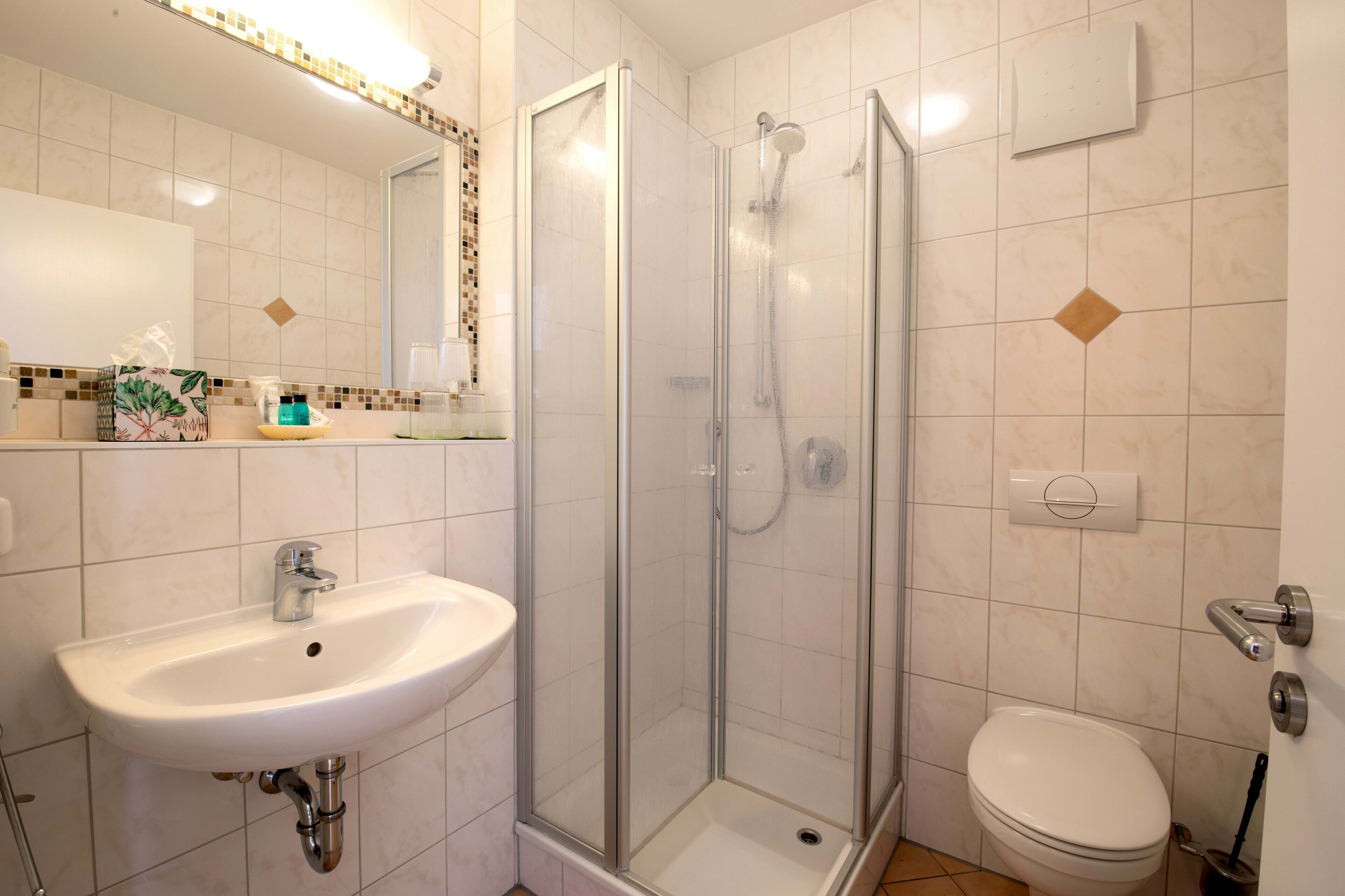 A bathroom with a sink, toilet, and glass-enclosed shower.