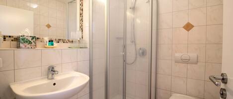 A bathroom with a sink, toilet, and glass-enclosed shower.