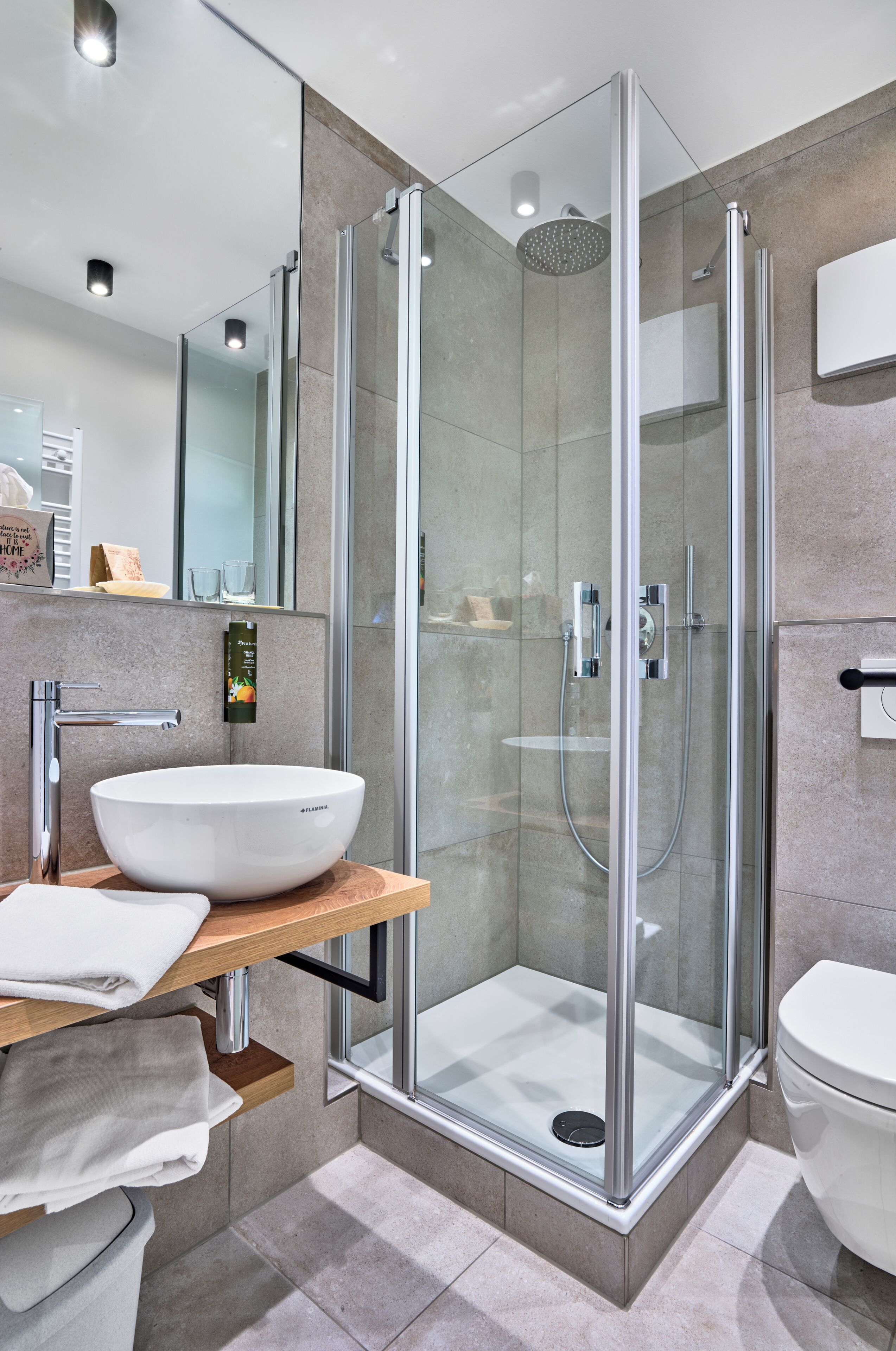 A modern bathroom with a glass-enclosed shower, a white sink, and a toilet.