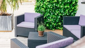 Un patio con mobiliario de mimbre y una planta en maceta.