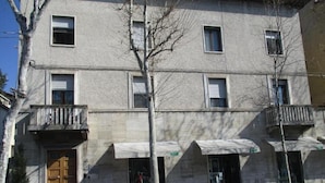 Un edificio de varios pisos con fachada de piedra, una puerta de madera y un balcón.