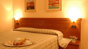 Una habitación de hotel con una cama, dos lámparas de pared y una bandeja con artículos de desayuno.