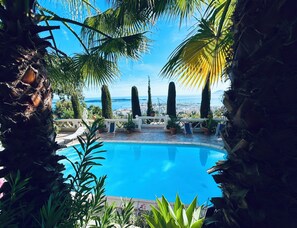 A pool surrounded by tropical plants and a view of the city. - Sumptuous mediterranean villa in Cannes (Cannes)