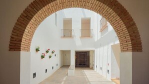 A spacious corridor with a high arched brick ceiling, white walls, and potted plants. - Tandem El Patio (Córdoba)
