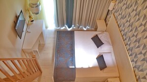 A bedroom with a bed, a desk, a TV, and a staircase. - Ouril Hotel Julia (Sal)