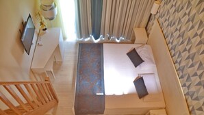 A bedroom with a bed, a desk, a TV, and a staircase. - Ouril Hotel Julia (Sal)