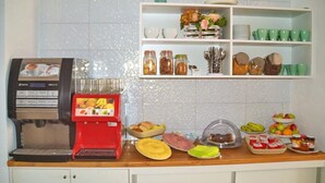 A breakfast buffet setup with a coffee machine, various food items, and a beverage dispenser. - Ouril Hotel Julia (Sal)