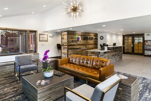 Welcome to our hotel lobby, featuring a central reception desk and comfortable seating area with a sofa and armchair.