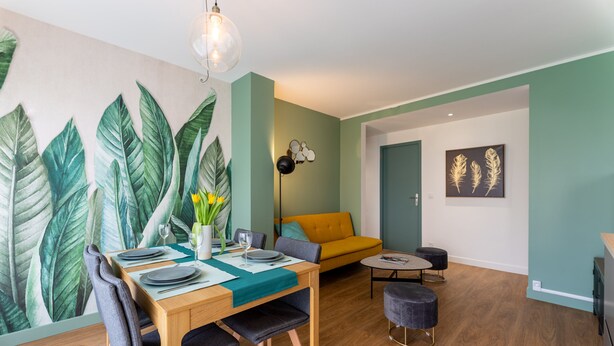 A dining area with a wooden table set for four, a sofa, and a small round table with two chairs.