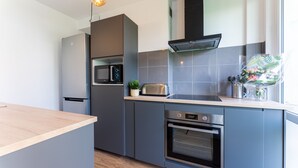 A modern kitchen with grey cabinetry, a built-in microwave, a toaster, and an oven.