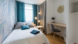 A bedroom with a bed, a desk, and a chair.