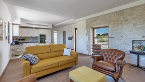 Een moderne woonkamer met een bank, een leren fauteuil en een bijzettafeltje.
