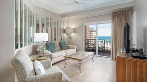 Relax in a comfortable seating area with a sofa and armchairs, and enjoy the ocean view through a large sliding door.