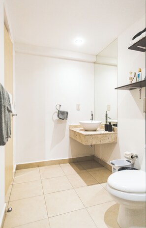 Features a large mirror, white sink, and toilet, along with a towel rack.