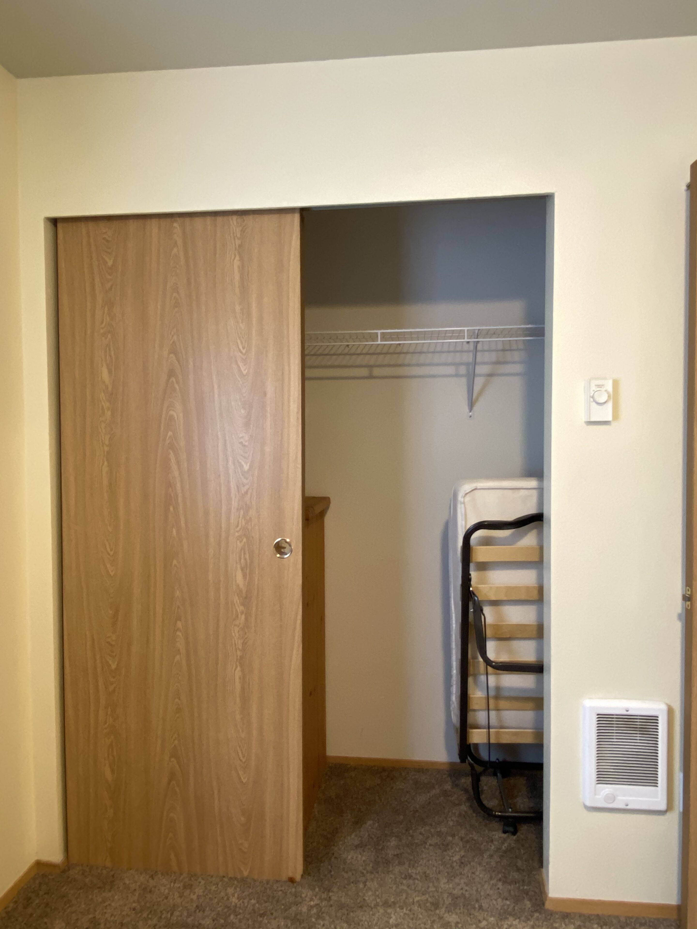 A room with a wooden door, a clothes drying rack, and a built-in heater.