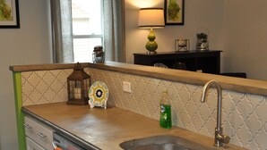 A kitchen with a double sink, wooden countertop, and a green accent wall. - Oswego Downtown District (Oswego)