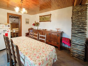 A dining area with a wooden table, chairs, a cabinet, and a stone wall.