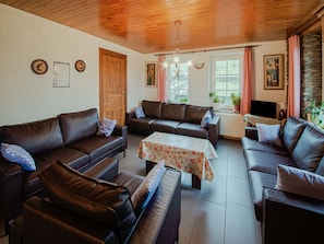 A furnished living room with leather sofas, a coffee table, and a television.