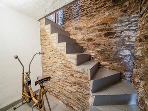 Uma escadaria com paredes de pedra, uma bicicleta e um corrimão de metal.