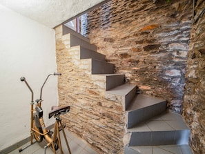 A staircase with stone walls, a bicycle, and a metal railing.