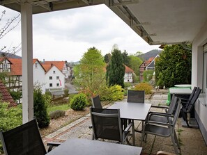 Eine Terrasse mit Sitzgelegenheiten, Blick auf traditionelle Häuser und einem klaren Himmel.