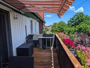 A wooden deck with a table and chairs, a small table with a bowl, and a potted plant. - Peaceful Apartment in Hüttenrode near Braunlage Ski Area (Blankenburg)