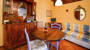 A wooden dining table with chairs, a sofa, a television, and a mirror. - Belvilla by OYO Casa Reale Quattro (Montecalvo Versiggia)