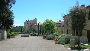 Ein Innenhof mit einem Kiesweg, umgeben von Steinmauern und unterschiedlichen Pflanzen.