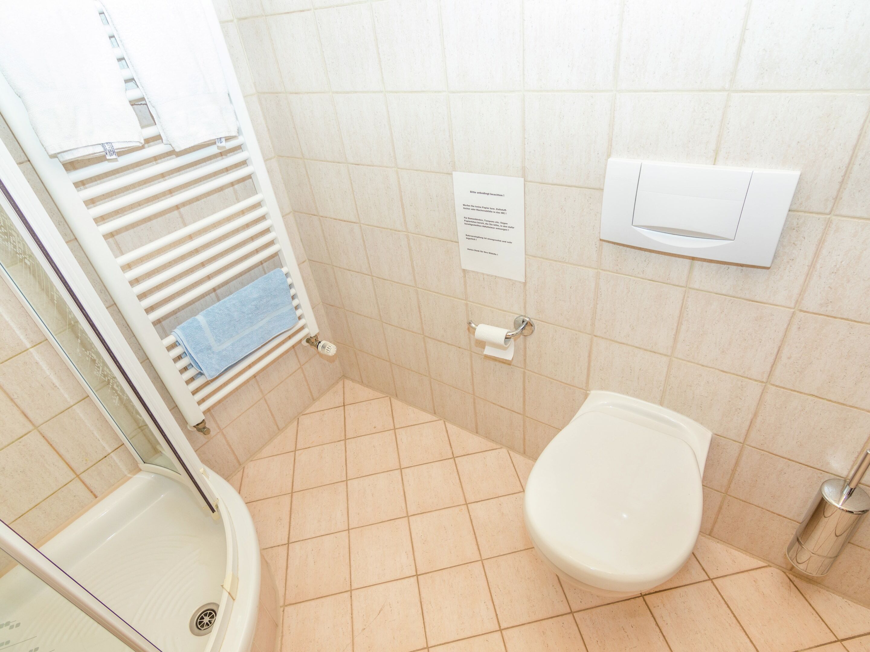 A small bathroom with a toilet, a shower, and a towel rack.