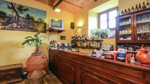 A bar area with a wooden counter, shelves with bottles, a television, and a mural on the wall. - Holiday Home Monte Santa Maria Pool Retreat (Monte Santa Maria Tiberina)