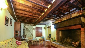 A cozy living room with a fireplace, a sofa, and a stone wall. - Holiday Home Monte Santa Maria Pool Retreat (Monte Santa Maria Tiberina)